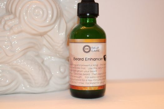 Bottle of QW Self Care's Beard Enhancer. All white background with a white dragon figurine