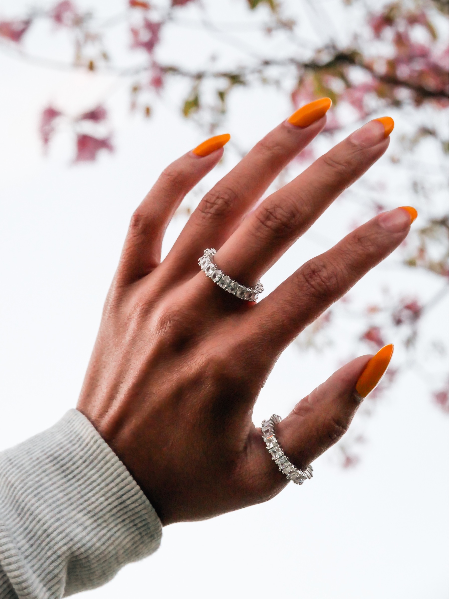 Brown womans hand wearing two amor deus ice rings