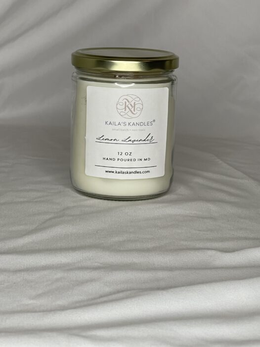 this is a clear glass jar with a gold top filled with fragrant candle wax. On the front is a white label with the name Kaila's Kandles and 12 ounces