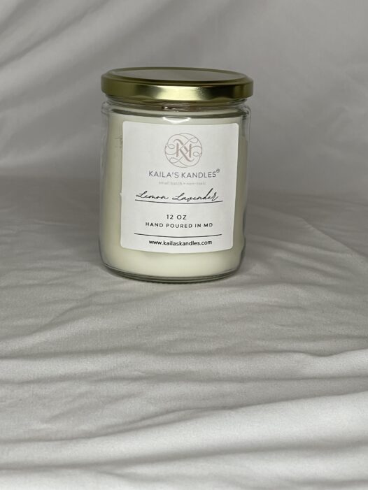 this is a clear glass jar with a gold top filled with fragrant candle wax. On the front is a white label with the name Kaila's Kandles and 12 ounces