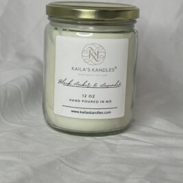 a clear glass jar with a gold top. Inside is filled with fragrant white candle wax. The front has a logo for Kaila's Kandles with the scent black amber and lavender listed on the front as well as 12 ounces