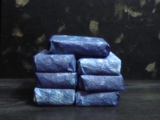 A stack of seven of soap wrapped in hand dyed blue wax paper