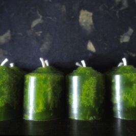 Multiple green votive candles in front of a dark background, ylang ylang and camphor scented