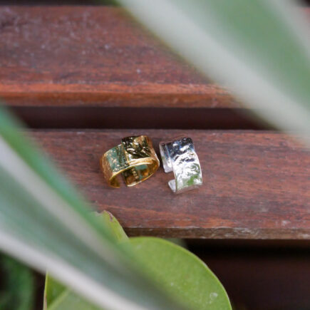 Gold and silver textured band rings on a wood shelf