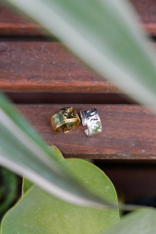 Gold and silver textured band rings on a wood shelf