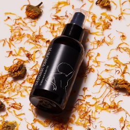 Body Oil surrounded by orange flower petals