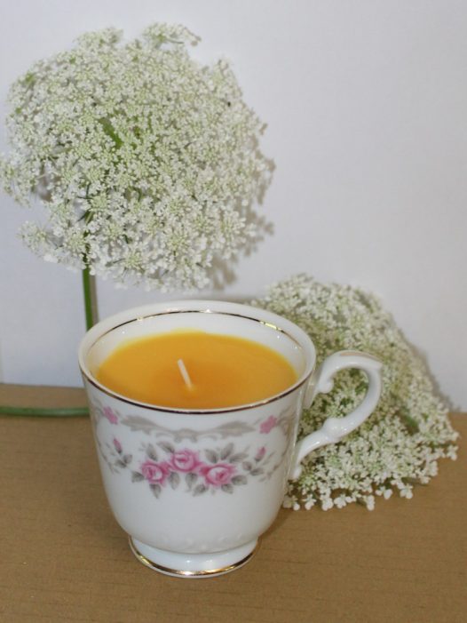 orange-colored teacup candle with Queen Anne's Lace flowers