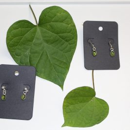 Two pairs of simple silver and green dangle earrings on a white background with morning glory leaves.