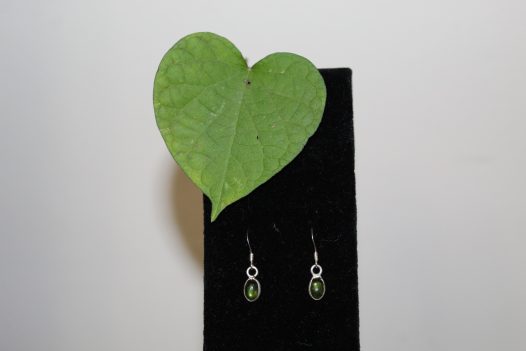 A pair of simple silver and green dangle earrings on a white background with a morning glory leaf.