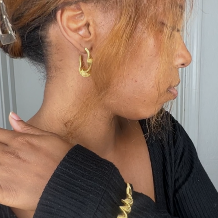 Gold twist bangle bracelet and hoop earrings on model 