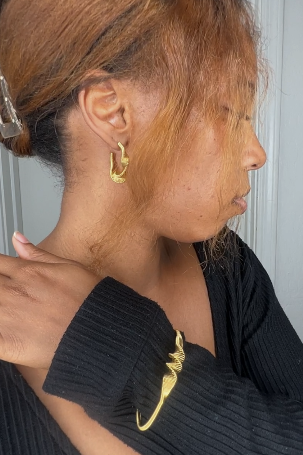 Gold twist bangle bracelet and hoop earrings on model
