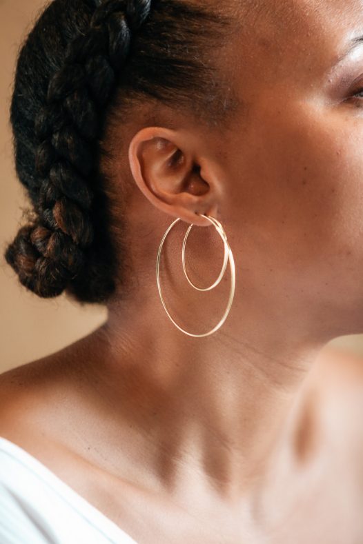 Size comparison of  medium and x-large the 14k gold Amor Deus Gold Classic Hoop Earrings.