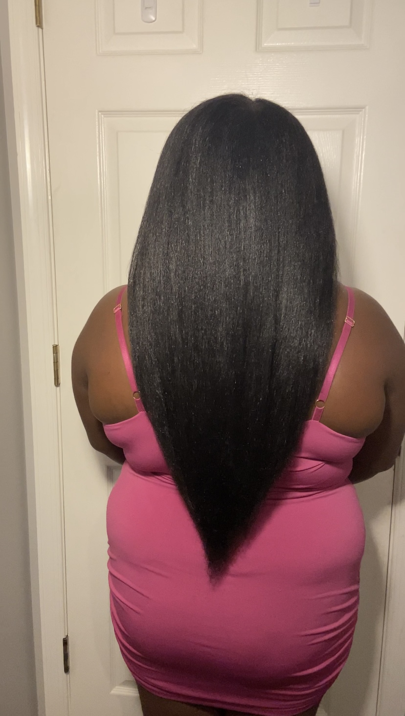 The creator of the Growth Training guide standing with her back towards the camera, to show the length of her natural hair also reaches her tailbone.